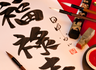 Caligraphy style Chinese characters next to ink and brushes