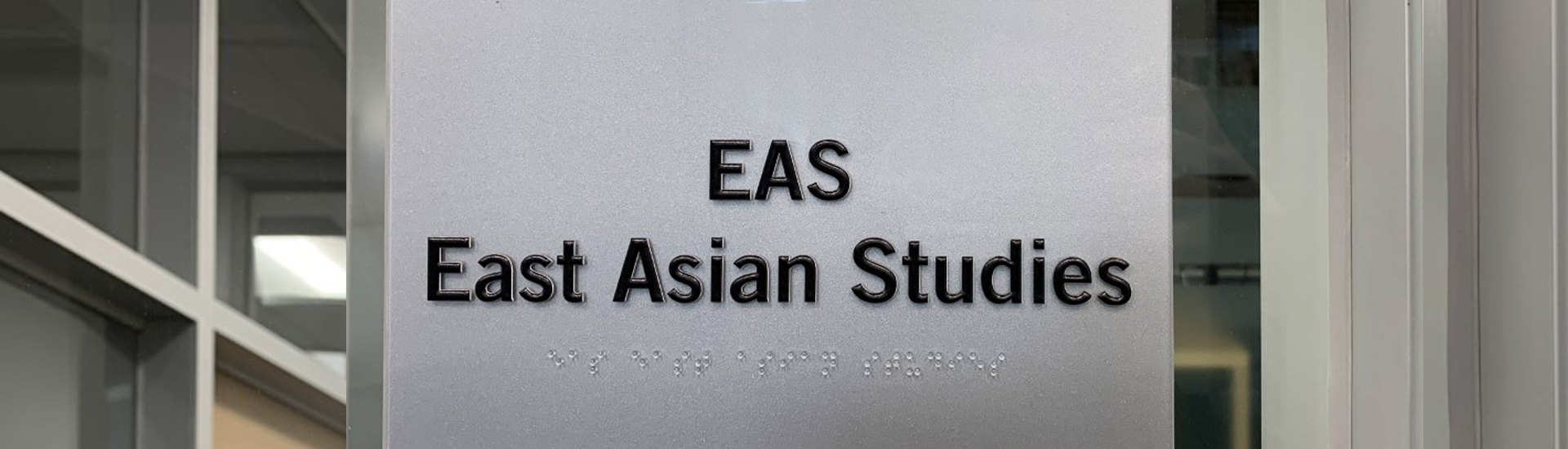 The phrase, "EAS - East Asian Studies," on a metal plate that is tacked onto a glass wall.
