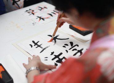 A woman paints Japanese characters.