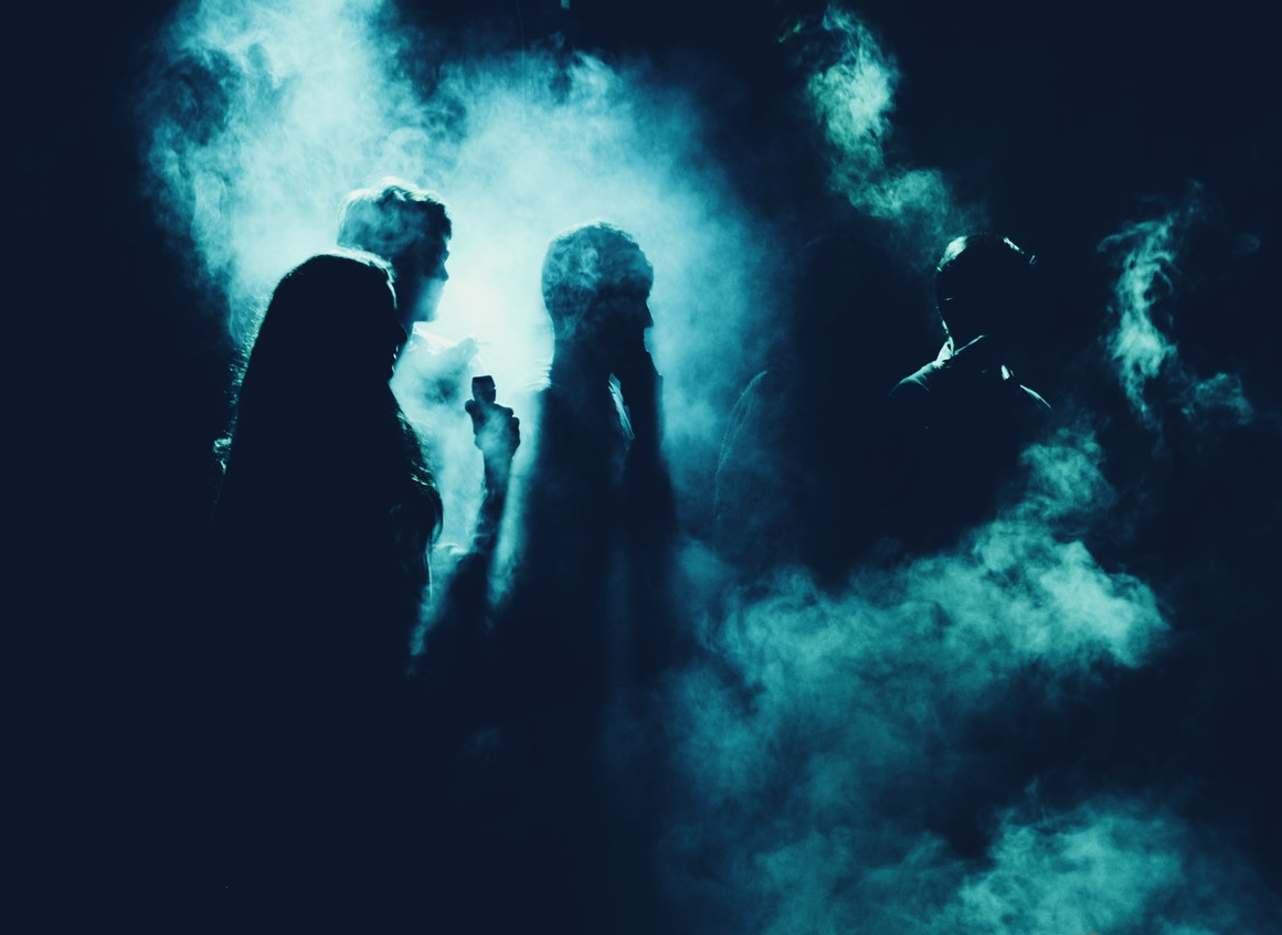 People standing in front of a smoke screen against a black backdrop, so they are only silhouettes.