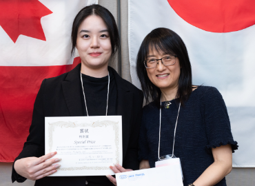 Michelle Lai holding her certificate next to Professor Ikuko Komuro-Lee with a backdrop of Canadian and Japanese flags