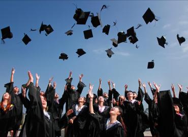 A group of students throw their graduation caps into the air.